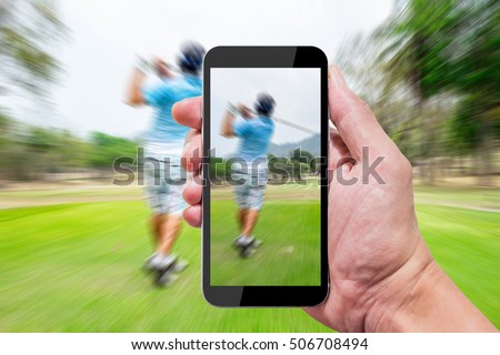 One using camera in smartphone capture still photo and record motion video when other swinging on golf teeing ground.