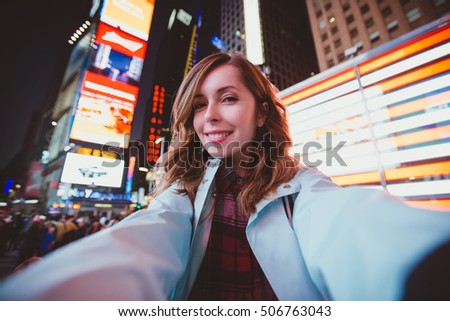 Young happy woman taking selfie on Times Square at night, Manhattan. Inspiring New York atmosphere and a beautiful smiling girl.