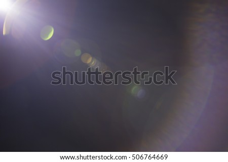 Solar camera lens flare light create ring of objective iris shapes of different rainbow colors depending on used antireflection coating of each lens surface on dark black background