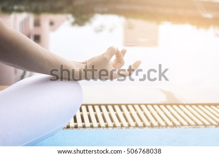 woman meditating with wrist beads in a yoga position.Close up view of the graceful hand gesture of a woman meditating overlooking a swimming pool with sun light.