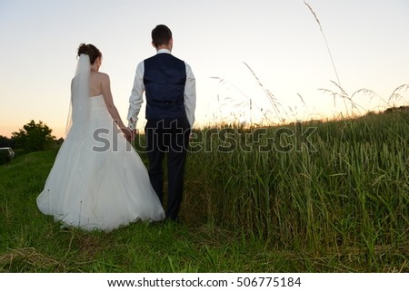 Bride and groom standing in a field picture from behind
