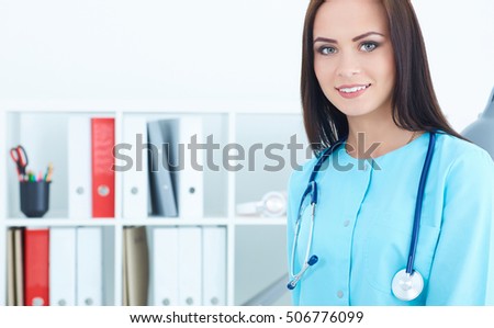 Beautiful smiling female medicine intern standing in her office looking in camera. Medical help or insurance concept. 