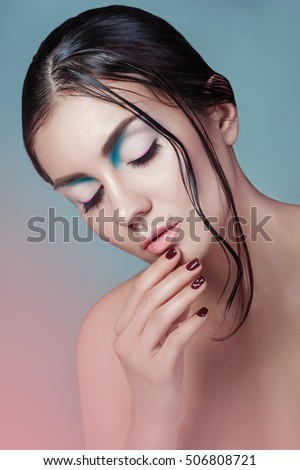 Brunette girl with fashion wet hairstyle and beautiful makeup on blue with pink effect background. Beautiful model with perfect makeup. Woman with beautiful hands hairstyle and makeup. 