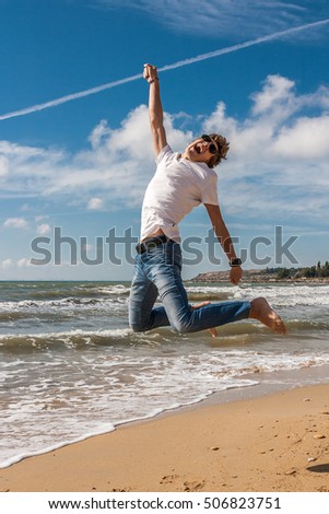 Young man jumping on the beach in the oncoming waves.
