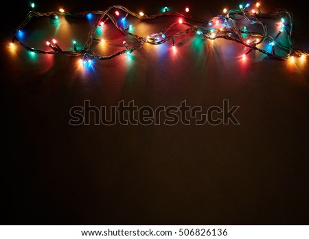 Christmas background with lights and free text space. Christmas lights border. Glowing colorful Christmas lights on black background. New Year. Christmas. Decor. Garland. Royalty-Free Stock Photo #506826136
