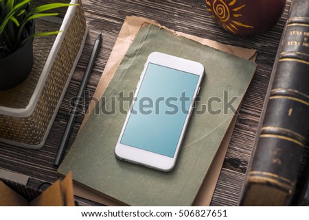 Template of white smartphone on the table with notes and old books. Clipping path