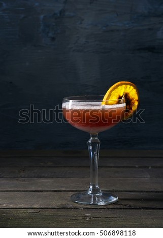 Alcohol cocktail drink with slice of orange on the wooden rustic background
