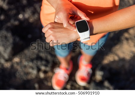 Trail runner athlete using her smart watch app to monitor fitness progress or heart rate during run cardio workout. Woman training outdoors on mountain rocks. Closeup of tech gear. Royalty-Free Stock Photo #506901910