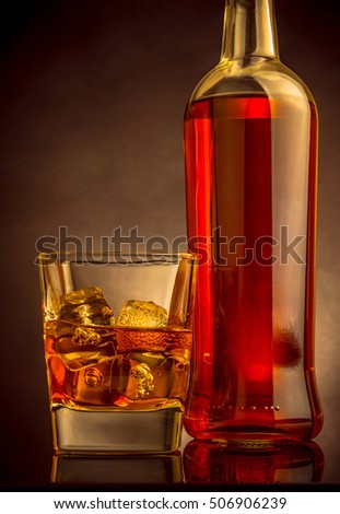 whiskey with ice cubes in glass near bottle on black background, warm atmosphere, time of relax with whisky