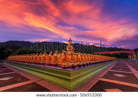 Big golden buddha statue and many small golden buddha statues sitting in row at at Buddha Memorial park, Nakornnayok Thailand.