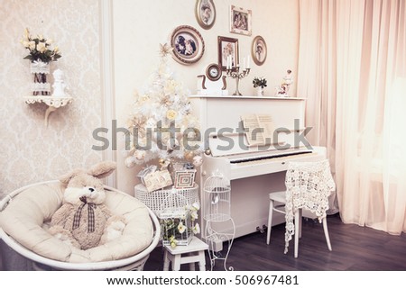 Xmas interior design includes white decorated Christmas tree with hand made ornaments, gift boxes under it and white piano. Winter scene. New Year decoration.