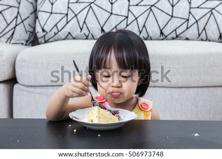 Moody Asian Chinese little girl eating birthday cheese cake at home indoor.