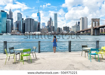 New York city skyline waterfront lifestyle - woman enjoying view. American people walking enjoying view of Manhattan over the Hudson river from the Brooklyn side. NYC cityscape with a boardwalk.