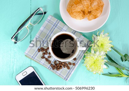 A cup of coffee with croissant on blue table background in the morning . take a break with fresh flower from garden - idea concept.