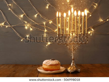 Low key Image of jewish holiday Hanukkah with menorah (traditional Candelabra) and donut
