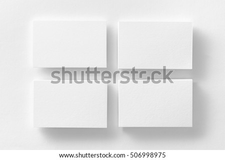 Mockup of four white business cards stacks arranged in rows at white design paper background.