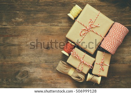 Flat lay image of handmade gift boxes over wooden background