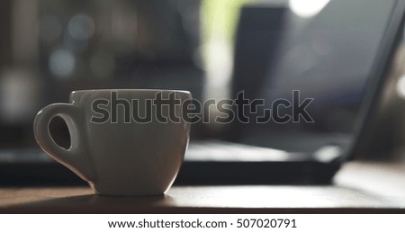 cup of espresso on table with notebook on background, very shallow focus