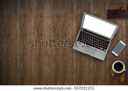 Desktop wooden office with laptop computer, note pad, smart phone and coffee of cup.Coffee cup on tree leaf in wood background.Copy space.
