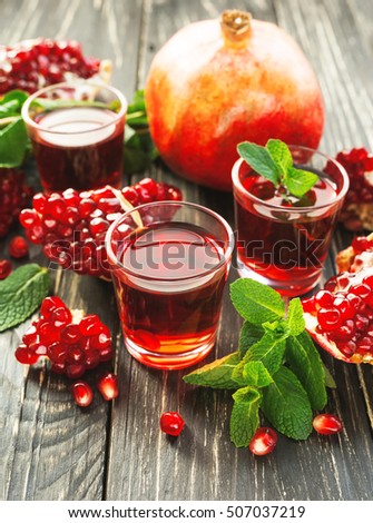 Pomegranate juice with fresh fruits and mint on wooden table. Healthy drink concept.