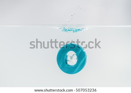 Blue wooden alphabet O drop in the water with white background and selective focus