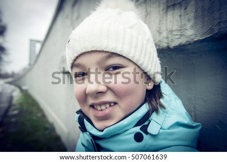 Close-up portrait of a smiling girl in a knitted hat. Street Photography. 
LOMO effect