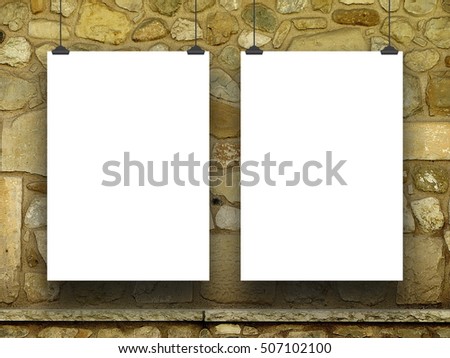 Two blank frames hanged by clips against ochre stone wall background
