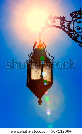 silhouette of old lantern hanging in bright sunlight