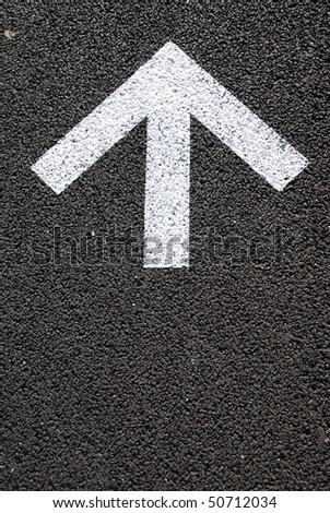 directional white arrow sign on the asphalt road