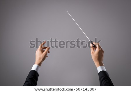 Concert conductor hand with baton isolated on grey background. Chorus composer holding baton during a opera. Musician directing concert. Close up hands of orchestra conductor with copy space. Royalty-Free Stock Photo #507145807