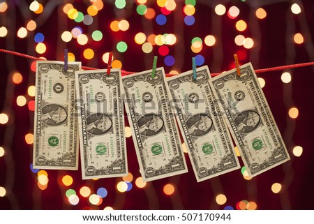 Dollars hanging on a rope on christmas lights background
