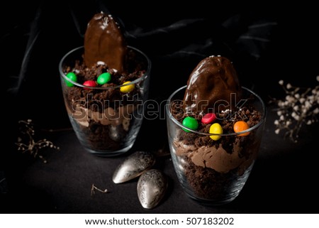 Chocolate graves for Halloween - Chocolate cake with chocolate cream, chocolate cookie and colorful candies in glass.
