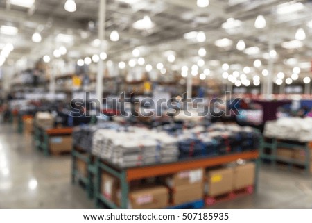 Blurred image huge variety of items at clothing section in modern distribution warehouse. Defocused background of storehouse interior aisle and rows. Inventory, wholesale, logistic and export concept.