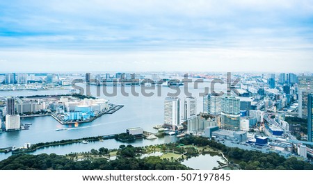 Business and culture concept - panoramic modern city skyline bird eye aerial view of Odaiba bay and rainbow bridge under dramatic morning blue cloudy sky in Tokyo, Japan

