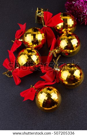 gold Christmas balls with red ribbons on a black background