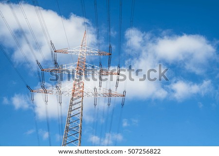 High voltage electricity pylon against blue cloudy sky