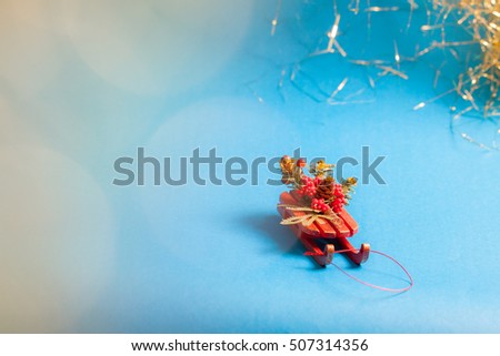 Christmas card with decorative sled standing on blue background in blurred glow balls.