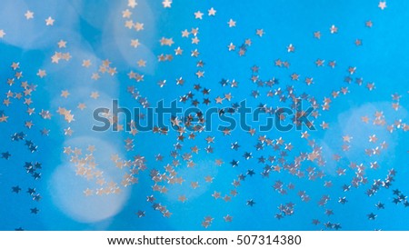 Little silver mirror stars scattered on blue background and fuzzy balls glitter.