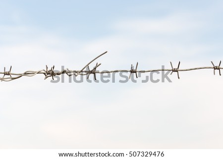 barbed wires against blue sky.