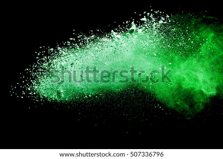 Green dust particle explosion resembling snow or a pyrotechnic effect over black. Closeup of a color explosion isolated on black