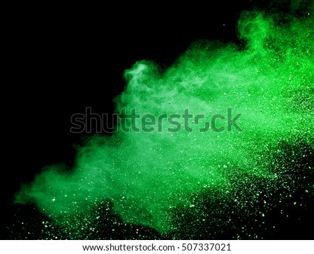 Green dust particle explosion resembling snow or a pyrotechnic effect over black. Closeup of a color explosion isolated on black