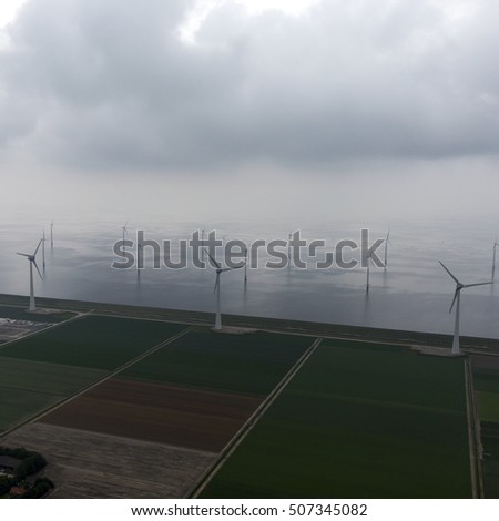 Aerial view of a windmillpark at Lake IJsselmeer in the province Flevoland, Netherlands. It is a dark, cloudy and rainy day.