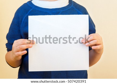 Children hands hold white paper sheet (empty blank) close up, copy space for text