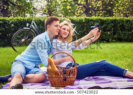 Loving couple doing selfie on a picnic in a park.