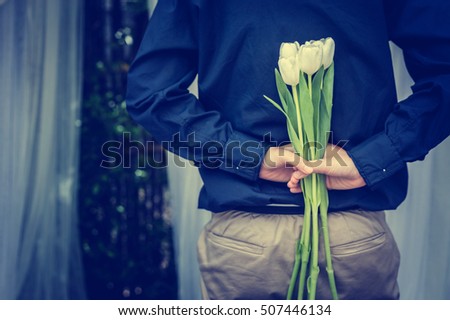 closed up hand hold tiny beautiful white flower in dark blue dress with garden background