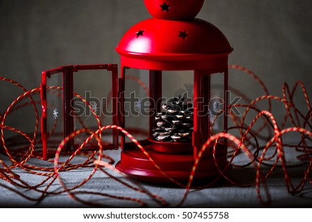 Christmas red lantern with a bump inside around twine, rope, canvas, in muted colors with one light source