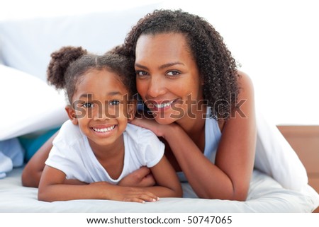 Affectionate woman and her daughter relaxing lying down on bed at home