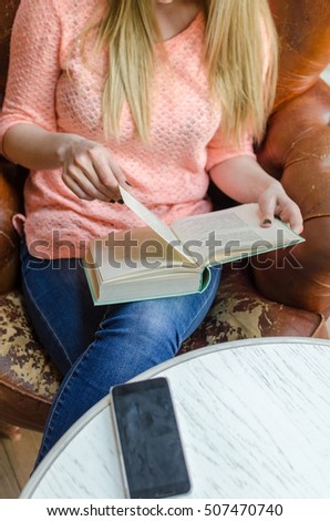 Young girl is sitting with the book in the room