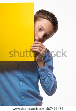 Emotional boy brunette in a blue shirt with yellow sheet of paper for notes on a white background