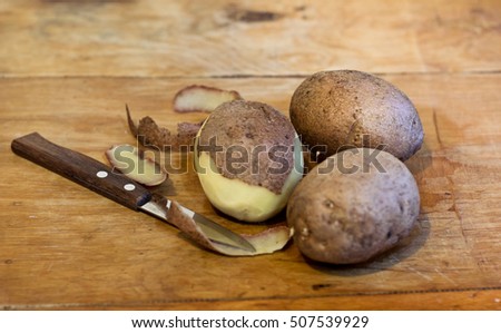 Potatoes and knife on old wooden table. Organic vegetarian food